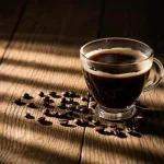 Cup of black coffee on a table with sun coming through a blind